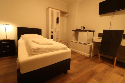 a bedroom with a bed and a desk and a chair at Schiller Pension in Bielefeld
