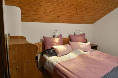 a bedroom with a bed with pink and white pillows at Haus am Römerbad in Bad Kleinkirchheim