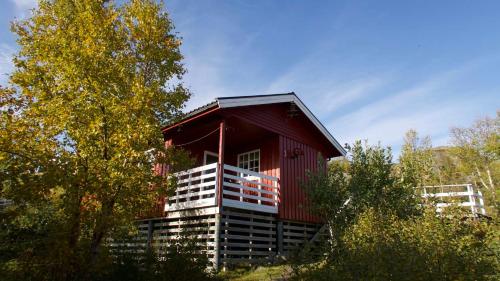 a red cabin in the middle of some trees at Offersøy Feriesenter in Offersøy