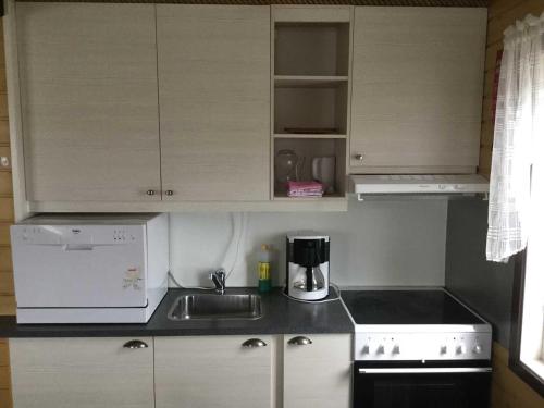 a kitchen with white cabinets and a sink and a coffee maker at Offersøy Feriesenter in Offersøy