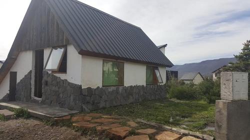 ein kleines weißes Haus mit einer Steinmauer in der Unterkunft Cabaña en Caviahue in Caviahue