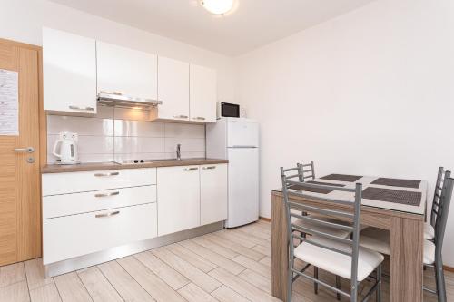 a kitchen with a table and a white refrigerator at Apartments Crnekovic Tomislava 8 in Baška