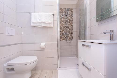a white bathroom with a toilet and a shower at Apartments Crnekovic Tomislava 8 in Baška