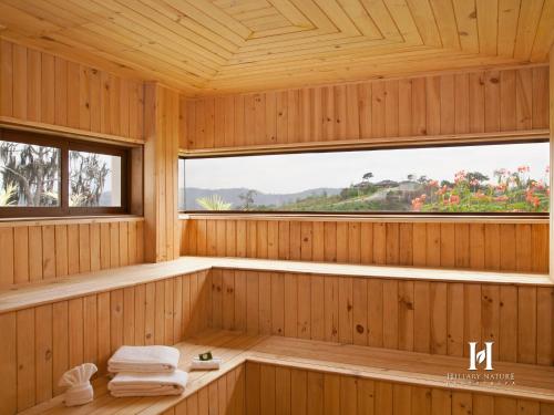 a wooden sauna with a tub and two windows at Hillary Nature Resort & Spa All Inclusive in Arenillas