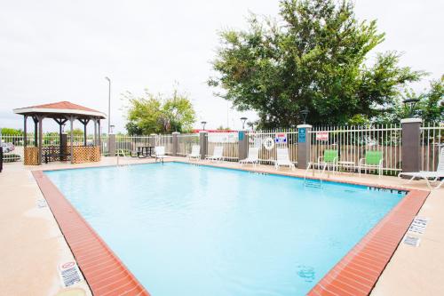 a large swimming pool with chairs and a gazebo at Palacio Royale Inn Boutique Katy in Katy