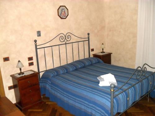 a bedroom with a bed with a blue striped blanket at Affittacamere Casa Sofia in Anghiari