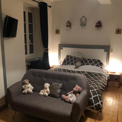 three teddy bears sitting on a couch in front of a bed at Chez Celine et Philippe Chambre atelier dans propriété de charme avec piscine in Le Fossat