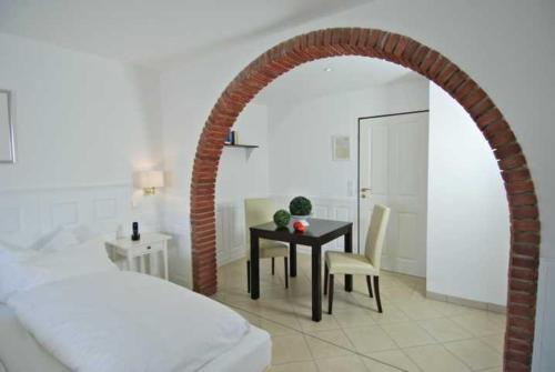 a bedroom with a table and a bed and an archway at Wohlfühlhotel Hörn van Diek Garni mit Schwimmbad in Bensersiel