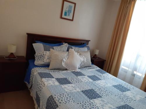 Un dormitorio con una cama azul y blanca con almohadas en Departamento en la Serena, en La Serena