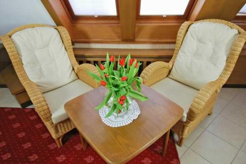 two wicker chairs and a table with a vase of flowers at Wohlfühlhotel Hörn van Diek Garni mit Schwimmbad in Bensersiel