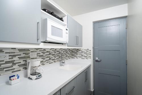 a kitchen with white cabinets and white appliances at South Gap Hotel in Christ Church