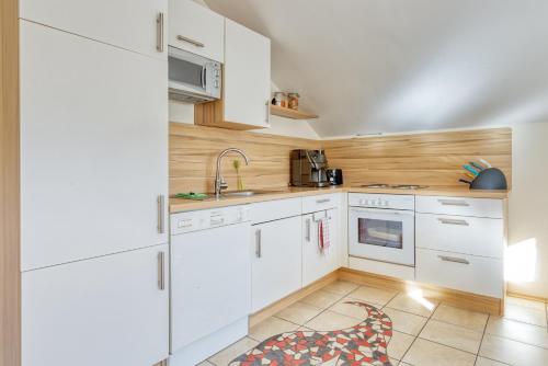 una cucina con armadietti bianchi e pavimento piastrellato di Appartment Stiegler a Haus im Ennstal