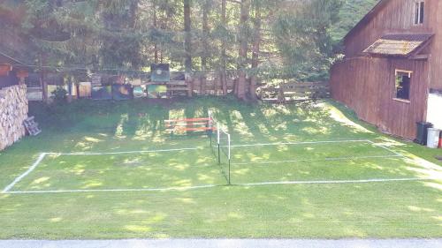a tennis court in a yard next to a barn at Ferienhaus Monika in Gutschau