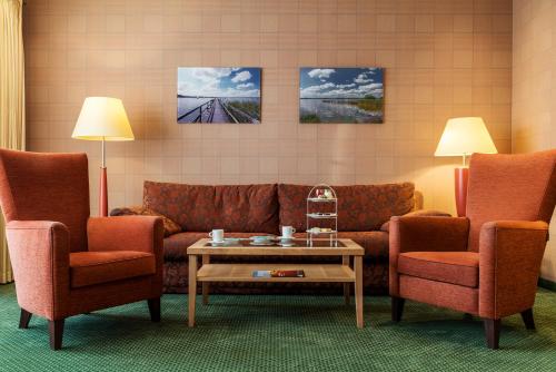 a living room with a couch and two chairs and a table at Romantik Hotel Jagdhaus Eiden am See in Bad Zwischenahn