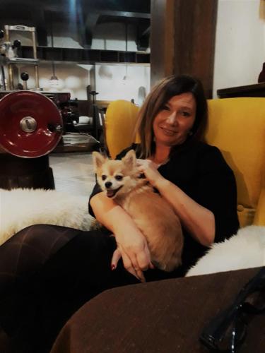 a woman sitting on a couch holding a small dog at Rooms Vodisek - Depandansa Hotela Capris Capodistria Boutique in Koper