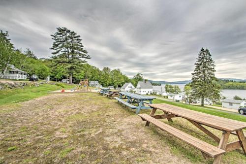 a row of picnic tables in a field next to a lake at Newfound Lake Studio BBQ, Fire Pit and Beach Access in Bristol