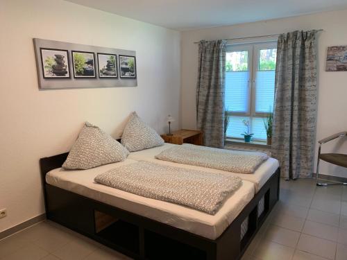 ein Schlafzimmer mit einem Bett mit zwei Kissen und einem Fenster in der Unterkunft Ferienwohnung Strandmaus, Ferienanlage "Blaumuschel" in Lubmin