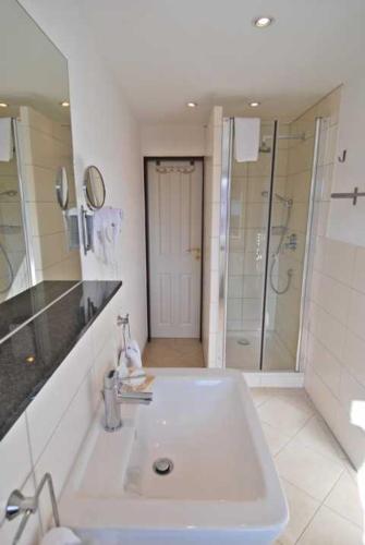 a white bathroom with a sink and a shower at Wohlfühlhotel Hörn van Diek Garni mit Schwimmbad in Bensersiel