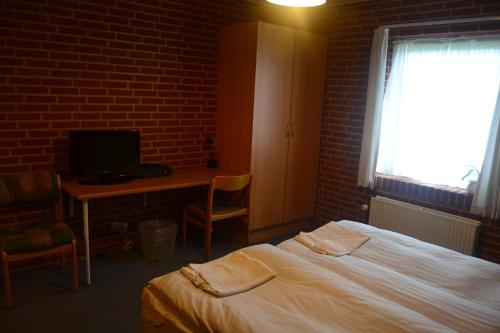a bedroom with a bed and a desk with a television at Paarup Kro in Engesvang