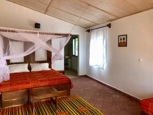 1 dormitorio con 1 cama con colcha roja en Les Barracudas, en Sokone
