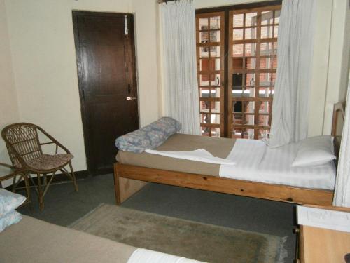 a bedroom with a bed and a window and a chair at Hotel Red Planet in Kathmandu