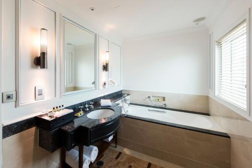 a bathroom with a sink and a bath tub and a mirror at InterContinental Singapore by IHG in Singapore