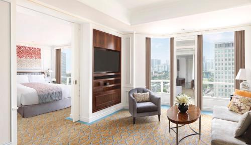 a hotel room with a bed and a tv and a couch at InterContinental Singapore by IHG in Singapore