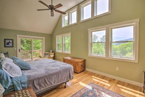 a bedroom with a bed with windows and a fan at Home with Fire Pit, 10min to Attitash Mtn Resort in Jackson