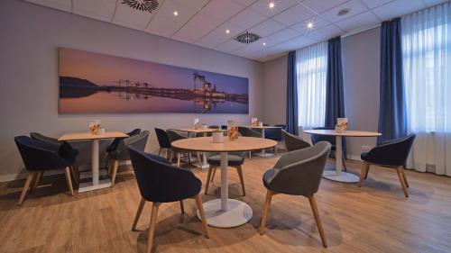 a room with tables and chairs and a painting on the wall at Holiday Inn Express Dortmund by IHG in Dortmund