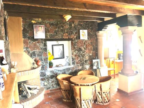 a room with a stone wall with a table and chairs at La Gloria de Los Ángeles in Tzintzuntzán