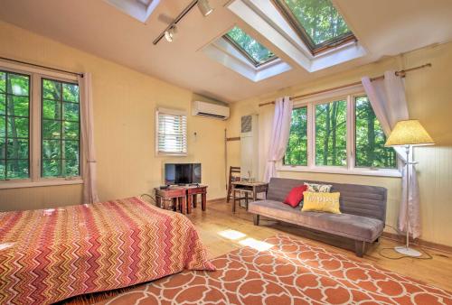 a bedroom with a bed and a couch and windows at Quiet Saugatuck Studio with Patio - Walk to Dtwn! in Saugatuck