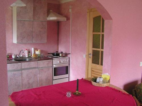 a pink kitchen with a table with a candle on it at Andrese Holiday Home in Muratsi