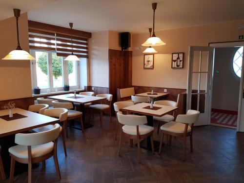 a restaurant with wooden tables and white chairs at Kavárna a penzion REICHL in Králíky