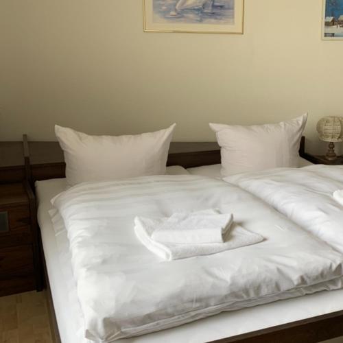 two white towels sitting on a white bed at Hotel Ellermann in Vlotho