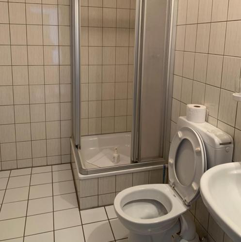 a bathroom with a toilet and a shower and a sink at Hotel Ellermann in Vlotho