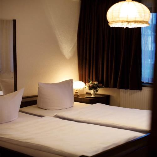 a bedroom with a bed with white sheets and a window at Hotel Ellermann in Vlotho