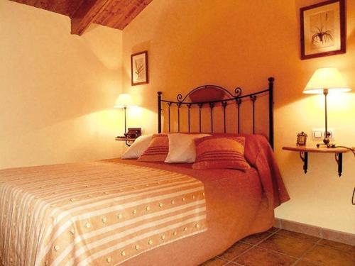 a bedroom with a bed with two lamps and a table at Apartamentos Turismo Rural Casa Santorroman in Campo