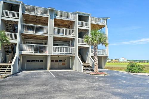 a large apartment building with a palm tree in a parking lot at Carolina Beach Home with Views and Pool Access! in Carolina Beach
