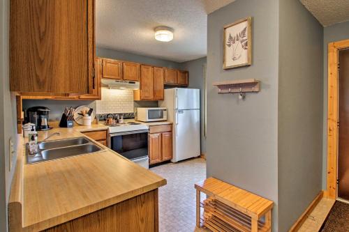 a kitchen with wooden cabinets and a white refrigerator at Lincoln Condo with Balcony - 6 Mi to Loon Mtn! in Lincoln