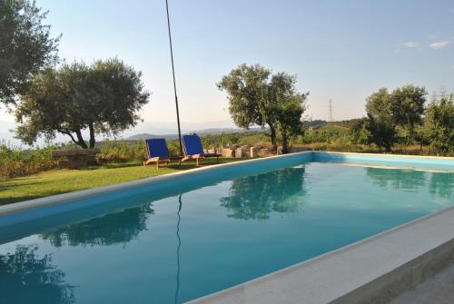 a swimming pool with two blue chairs and trees at Casa de Sao Miguel Douro in Armamar