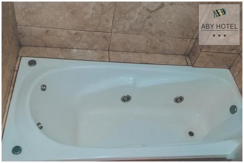 ABY Hotel في رامالو: حوض استحمام أبيض يجلس بجوار صندوق من الكرتون