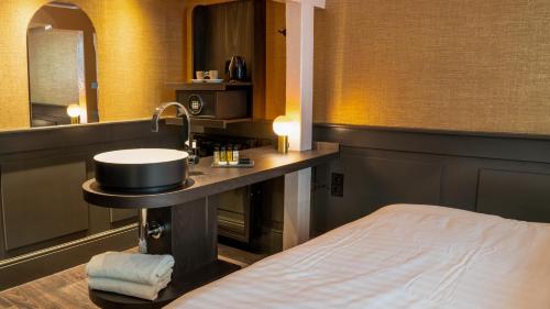 a bathroom with a sink and a bed in a room at Hotel Frank since 1666 in Amsterdam