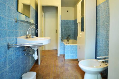 a blue tiled bathroom with two sinks and a toilet at Du côté de chez Marthe in La Cresse