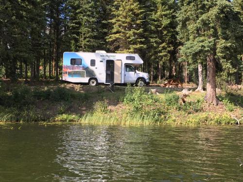 a white camper parked next to a body of water at Wettstone Guest Ranch in Bridge Lake