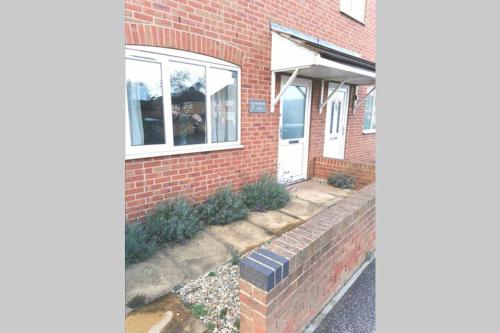 uma casa de tijolos com uma porta branca e uma parede de tijolos em Lavender House em Edwinstowe