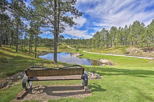 a park bench sitting in the grass next to a lake at Black Hills Cabin Hot Tub, Fishing Pond and Deck in Custer