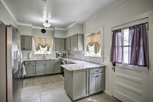 a kitchen with gray cabinets and a sink and a window at Charming Cottage with Mississippi River Views! in Natchez