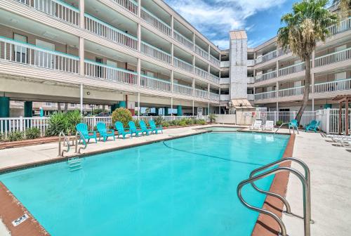 a swimming pool with chairs and a building at Beachfront Corpus Christi Condo with Arcade Room! in Corpus Christi