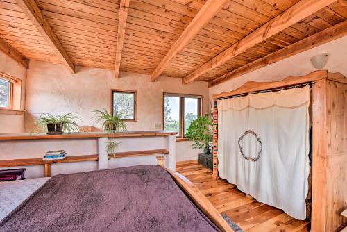 a bedroom with a bed in a room with wooden ceilings at Eclectic Adobe Crestone Cottage with Patio and Yard! in Crestone