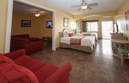 a hotel room with two beds and a couch at Ramada by Wyndham & Suites South Padre Island in South Padre Island